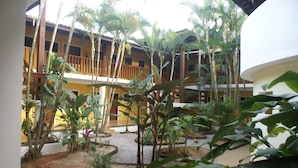 A courtyard with a pool, surrounded by plants and a building with balconies. - Pousada A Cor do Sol (Ubatuba)