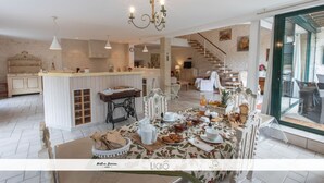 A spacious kitchen with a central island, a dining area with a table set for a meal, and a staircase leading to an upper level.