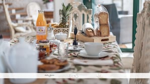 A breakfast table with a bottle of orange juice, bread, a pineapple, and various breakfast items.
