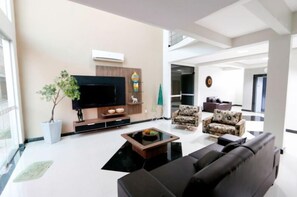 Una sala de estar moderna con un televisor de pantalla plana, una mesa de centro y dos sofás estampados.
