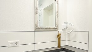 Ein modernes Badezimmer mit einem großen Spiegel, einem Waschbecken und einem Handtuchhalter.