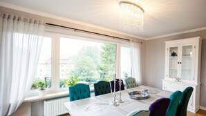 Ein Essbereich mit einem Tisch für vier Personen, einer Chandelüster und Blick ins Freie.