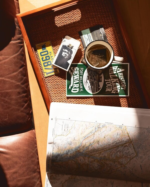 A wooden tray with a map, a book titled 'A History of Walking Tours', a coffee cup, and a small object on a woven surface.