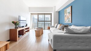 Un salon moderne avec un canapé gris, une table basse en bois et un téléviseur posé sur un meuble en bois.