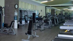 Une salle de sport équipée de tapis de course, d’appareils de musculation et d’un distributeur d’eau.