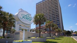 A sign for Ocean Forest Plaza with a modern building in the background.