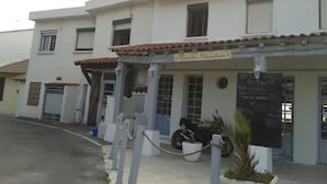 En restaurant, La Mediterraneé, med et skilt, et overdækket udendørs siddeområde og en motorcykel parkeret foran.