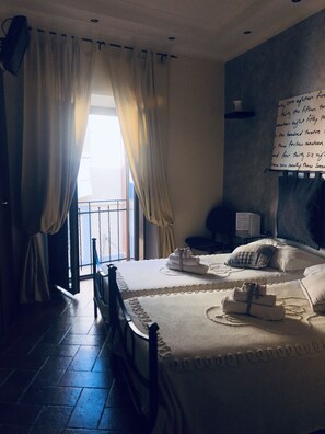 A bedroom with two beds, a window with curtains, a bedside table, and a wall with a handwritten note. - La Locanda del Borgo (Monte Porzio Catone)