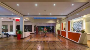 Hall d'albergo con reception, area salotto e pavimento piastrellato.