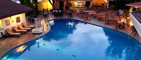 A swimming pool with lounge chairs and a bar area.