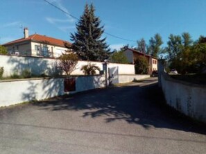 A residential street with houses, a large evergreen tree, and a clear sky. - Chambres des Arrys (Bas-en-Basset)