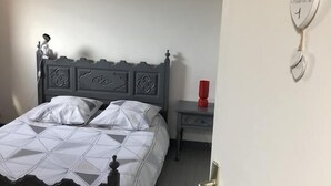 A bedroom with a bed, a nightstand, and a wall-mounted heart-shaped decoration. - Chambres des Arrys (Bas-en-Basset)