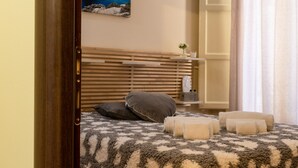 Un dormitorio con cabecera de madera, manta estampada y dos almohadas.