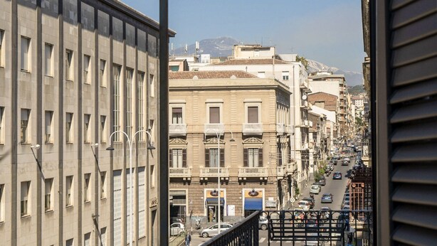 Vista de una calle urbana con edificios, una montaña al fondo y cielo despejado.