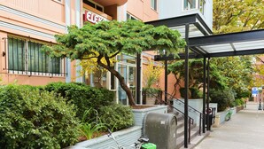 En grøn cykel parkeret ved en postkasse langs et fortov med en bygning i baggrunden.