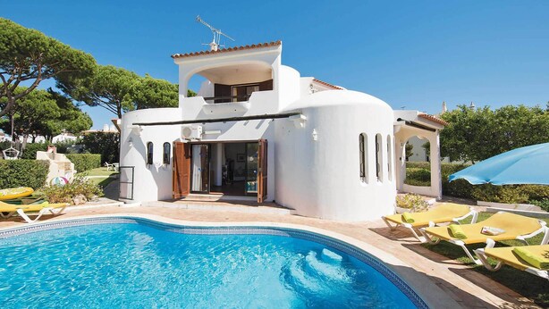 Une villa blanche à deux étages, dotée d’une piscine, d’un espace salon extérieur et d’un jardin.