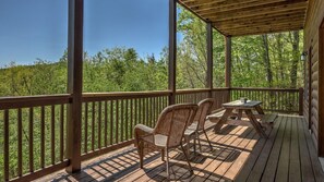A wooden deck with two wicker chairs and a table, overlooking a forested area. - TreeTops- Pet Friendly | Master on Main | 5 minutes from Downtown Blue Ridge (Blue Ridge)