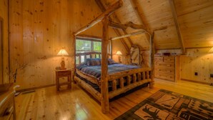 Un letto a baldacchino in legno con copriletto a quadri, due lampade sui comodini e una finestra con vista sul verde.