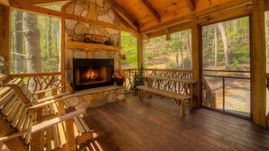 Una baita con camino in pietra, panche di legno e vista sulla foresta.