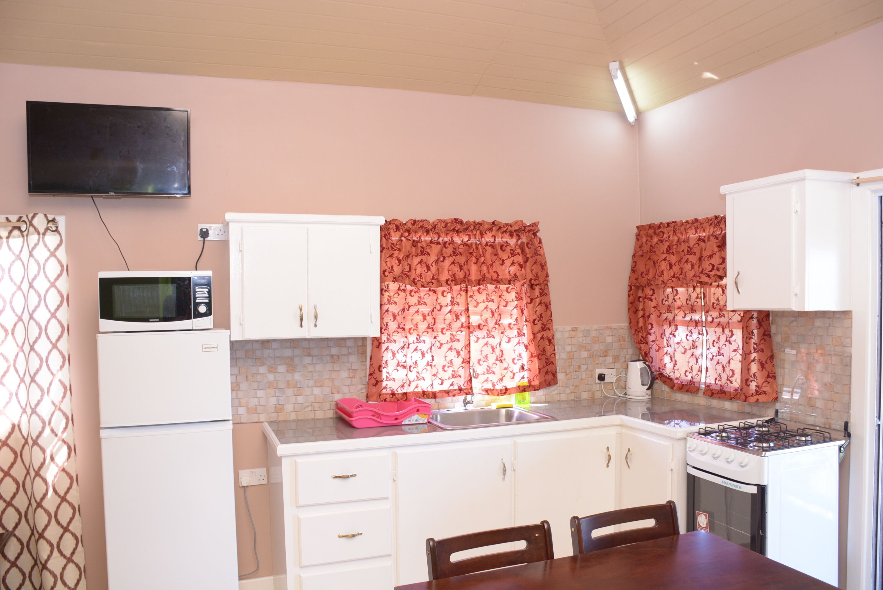 A compact kitchen with white cabinets, a microwave, a stove, and a sink.