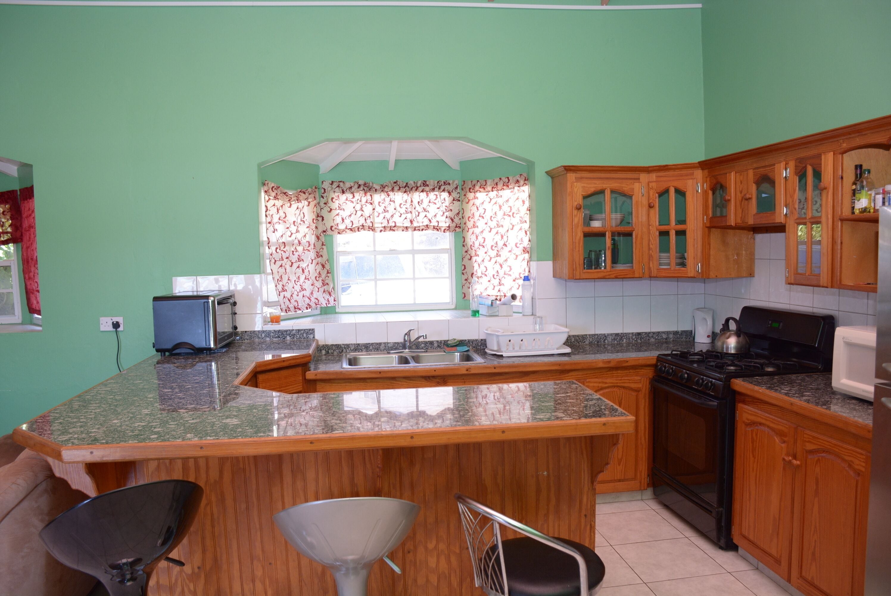 Una cocina con encimera de granito, armarios de madera, estufa y fregadero.