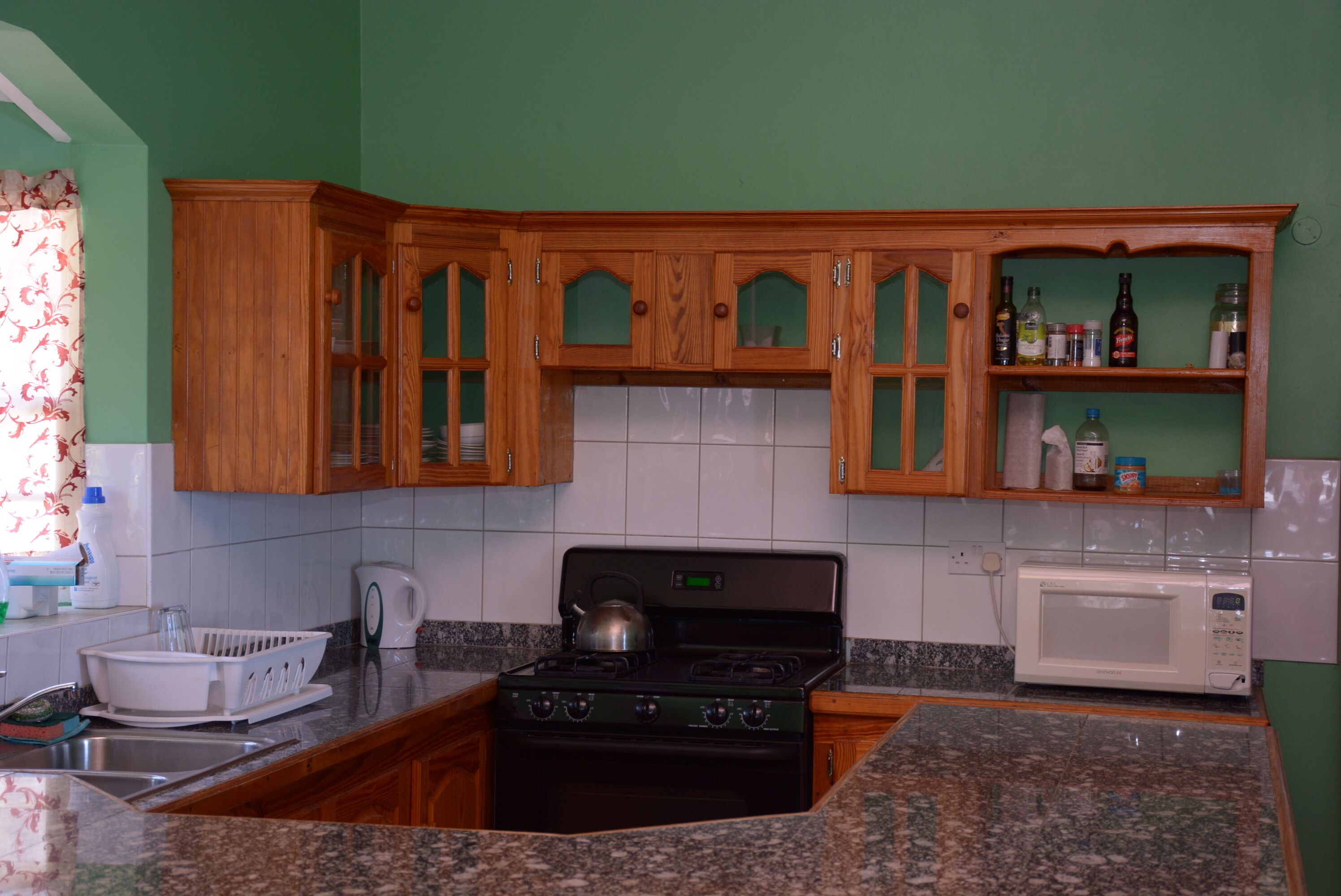 A kitchen with wooden cabinets, a stove, a microwave, and a sink.
