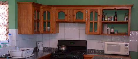 A kitchen with wooden cabinets, a stove, a microwave, and a sink.