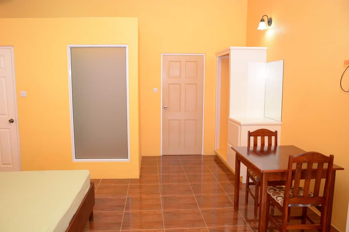 A room with a bed, a dining table with chairs, a wardrobe, and a door.