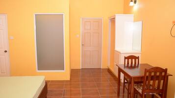 A room with a bed, a dining table with chairs, a wardrobe, and a door.