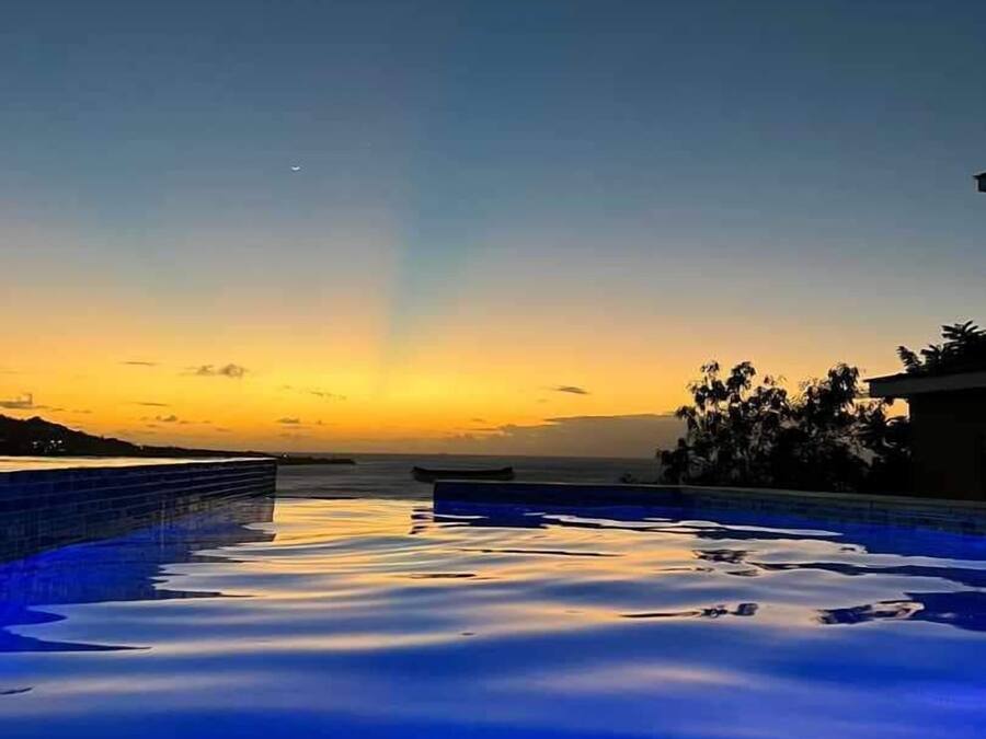 Une piscine au coucher du soleil, sous un ciel dégagé.