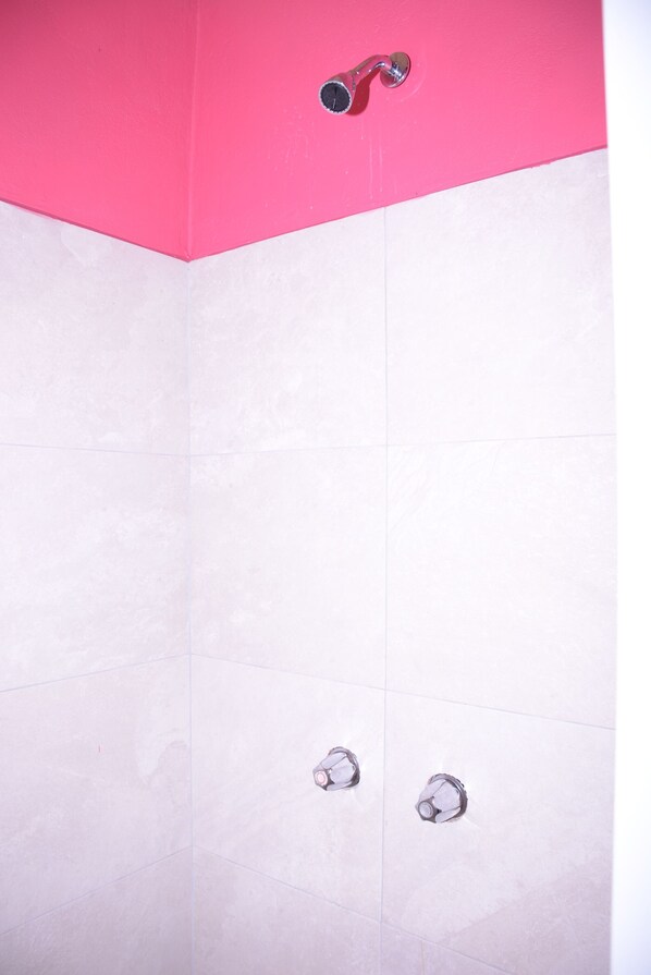 Un baño con pared rosa y suelo de baldosas blancas.