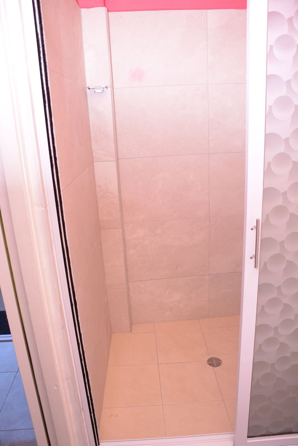Una ducha sin barreras con azulejos color beige y una puerta blanca.