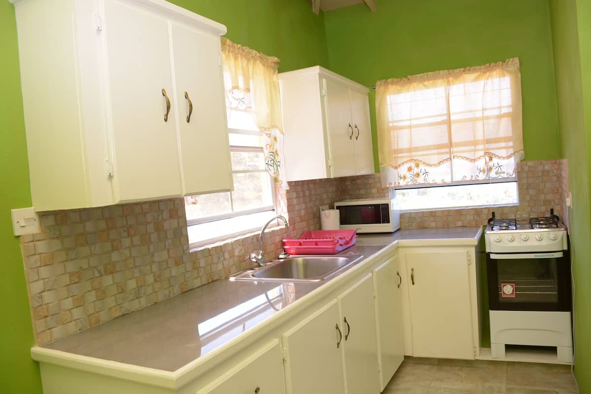 A kitchen with white cabinets, a sink, a microwave, and a stove.