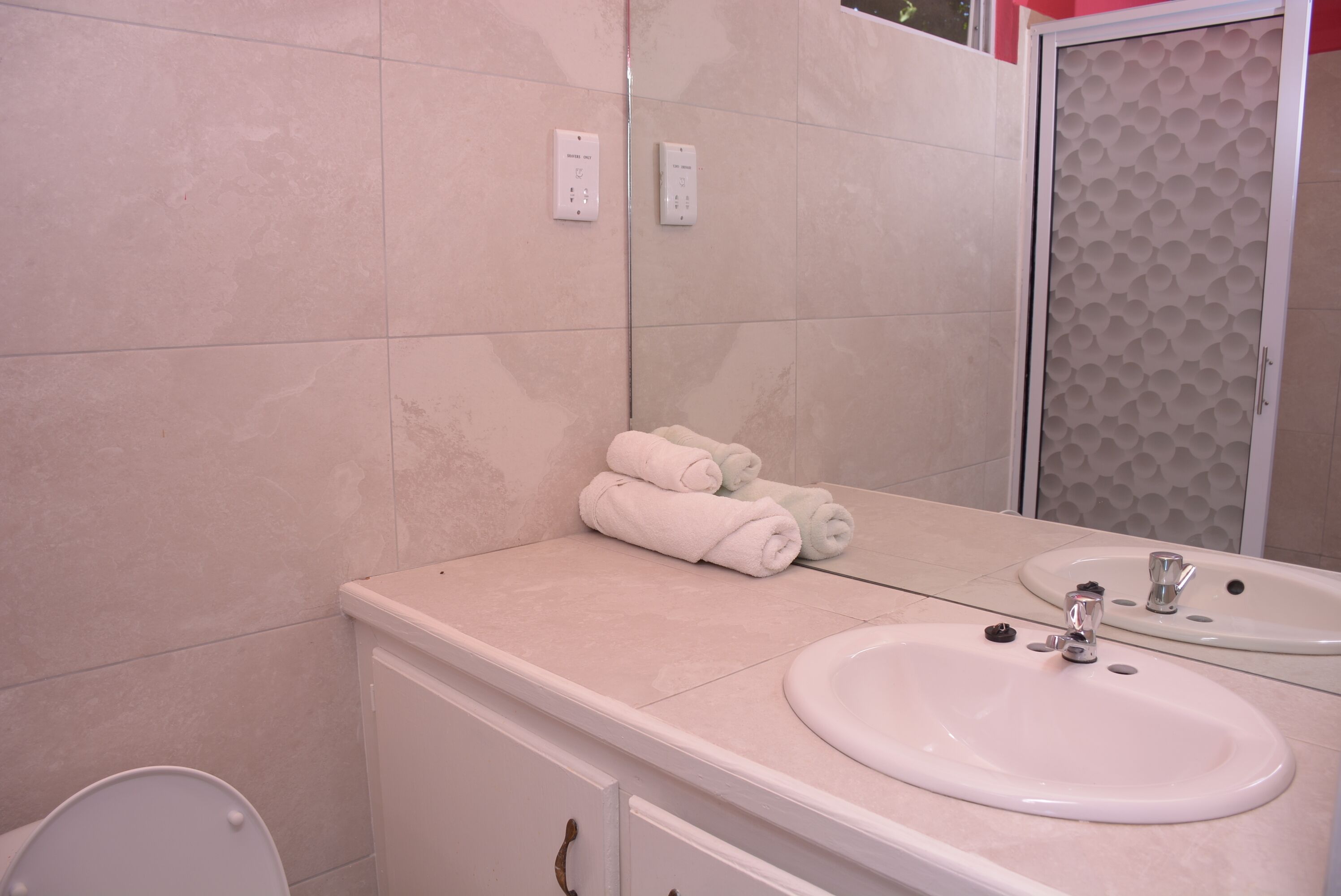 A bathroom with a white sink, a mirror, and a towel rack with folded towels.