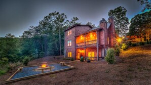 A rustic two-story wooden house with a balcony, surrounded by a forested area. - Sleepy Bear Hideaway - Close to Train, Mountain Views, Hot Tub (Blue Ridge)