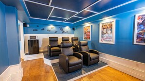 Une salle de cinéma maison avec des murs bleus, un plancher en bois et quatre fauteuils inclinables.