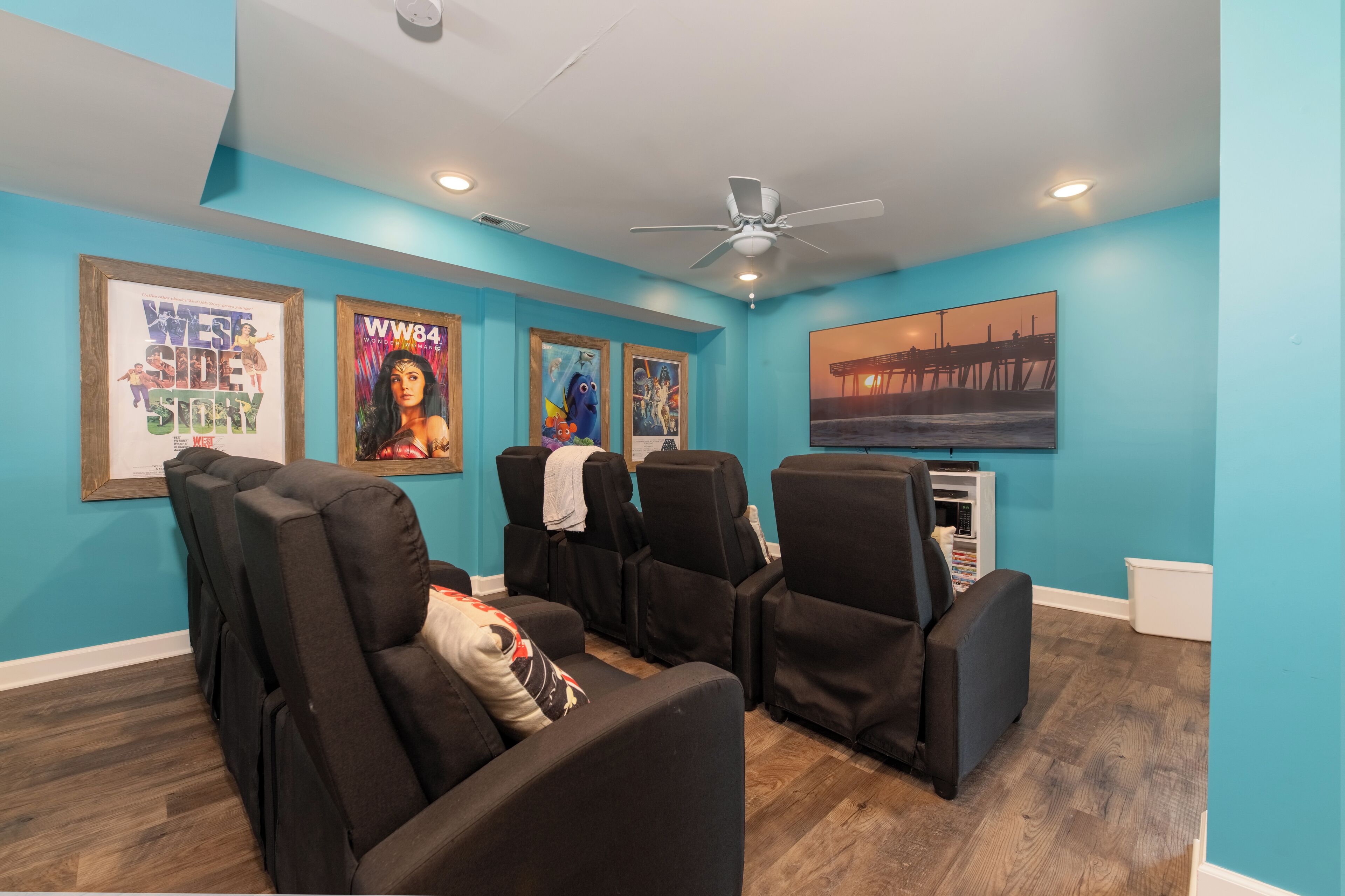 A room with teal walls, black massage chairs, and posters on the wall.