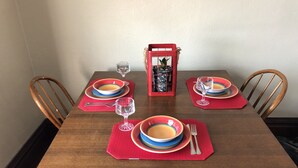 Una mesa de comedor dispuesta con platos, cubiertos y vasos, rodeada de sillas de madera.