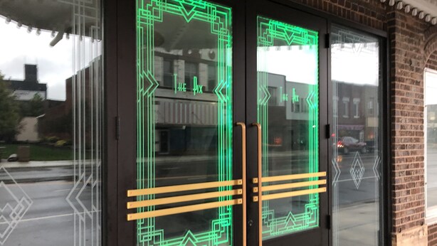 Un edificio con puerta de vidrio que presenta patrones geométricos y manijas.