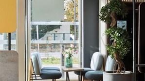A modern interior with two chairs, a table, and a large potted plant. - B&B HOTEL MASSY Gare TGV (Massy)