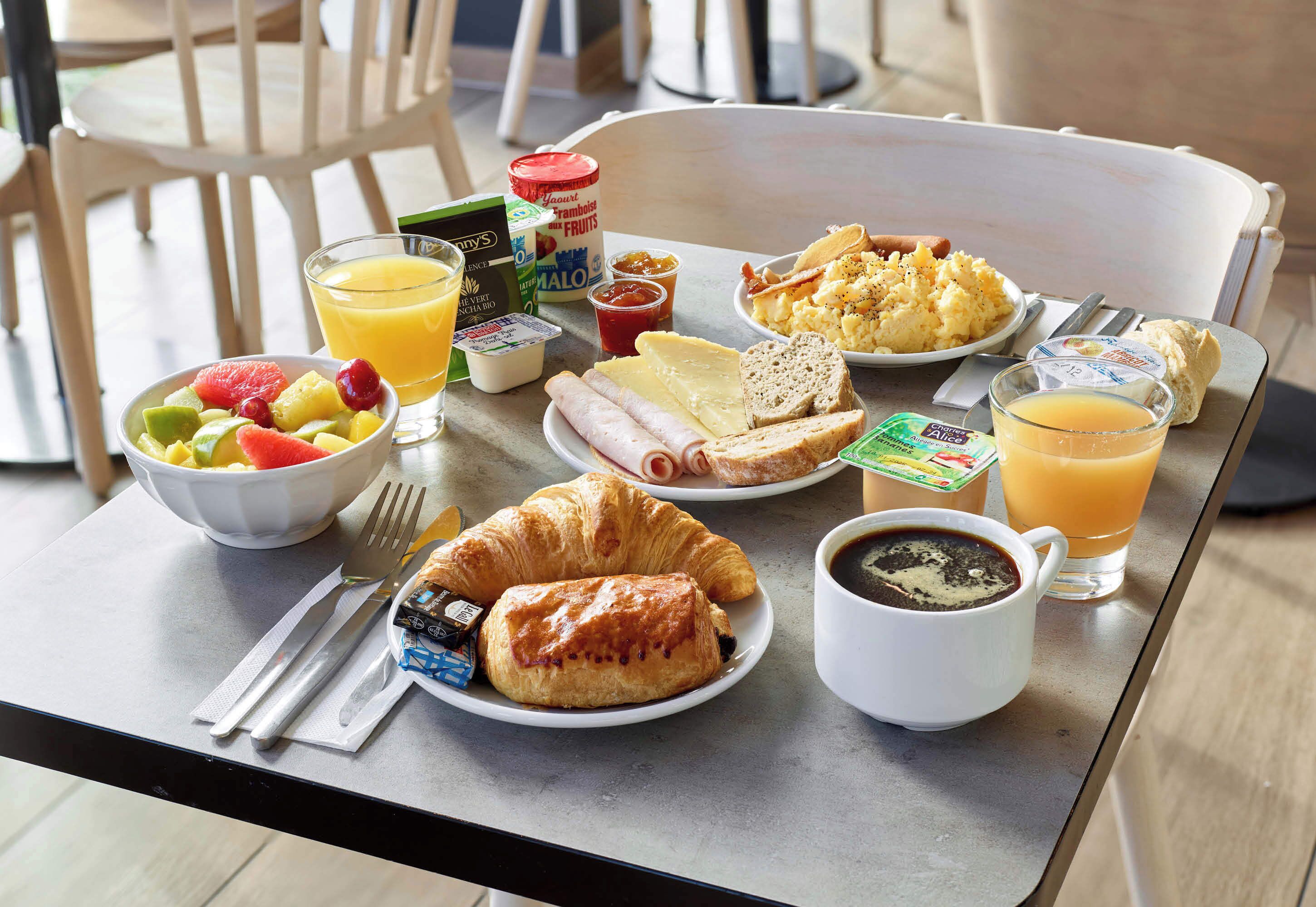 A breakfast table with croissants, fruit, scrambled eggs, toast, and coffee.