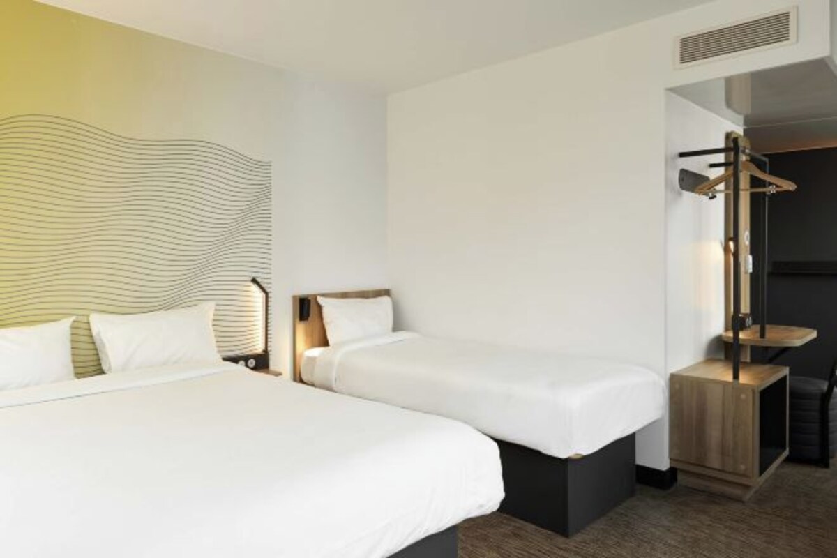 A hotel room with two beds, a desk, and a chair.