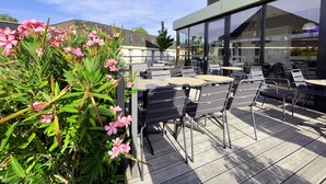 Un patio al aire libre con mesas y sillas, rodeado de follaje y flores.