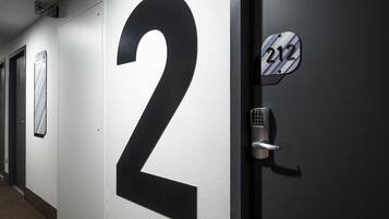 A hallway with a large number '2' on the wall, a door with a keypad lock, and a sign with the number '212'.