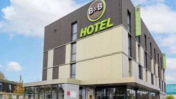 Un hotel tipo B&B moderno con un letrero llamativo, ventanas amplias y una fachada plana.