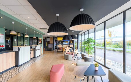A modern interior with a reception desk, seating area, and large windows offering a view of the outside.
