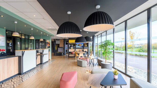 Un interior moderno con mostrador de recepción, zona de estar y ventanas amplias que ofrecen vistas al exterior.
