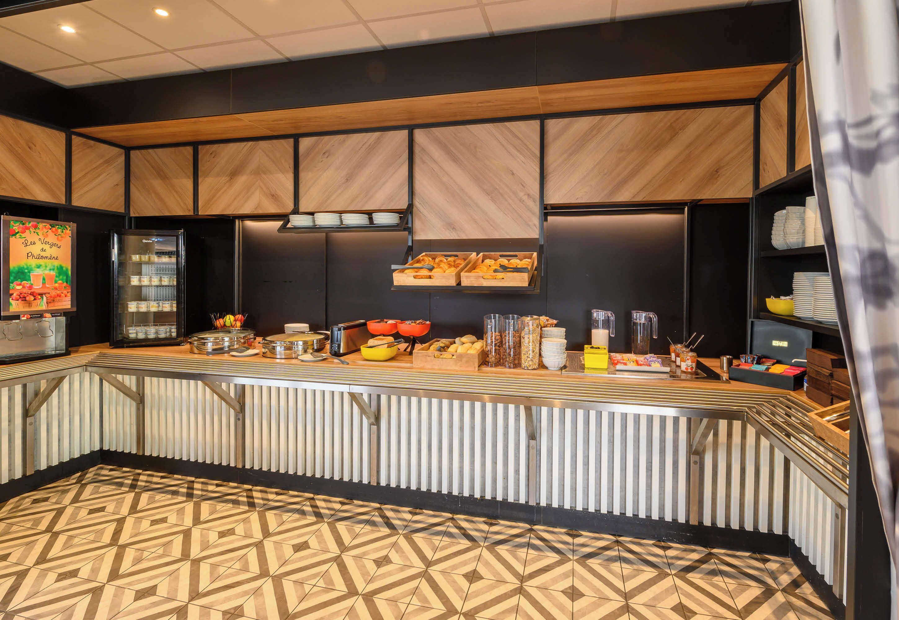 Una barra de desayuno moderna con piso de diseño geométrico, paneles de madera en las paredes y diversas opciones para el desayuno a la vista.