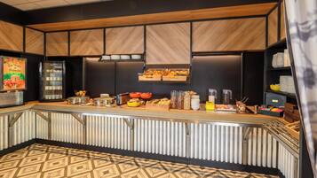 Una barra de desayuno moderna con piso de diseño geométrico, paneles de madera en las paredes y diversas opciones para el desayuno a la vista.