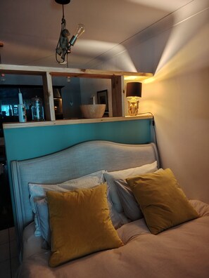 A bed with a headboard, two pillows, a bedside lamp, and a hanging light fixture.